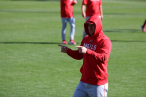 Mike Trout pointing to our left with both index fingers wearing Angels spring training apparel