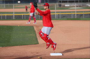 Logan O'Hoppe in catching gear at first base hopping into the air to catch a thrown ball