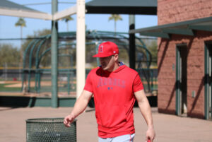 Mike Trout in red top walking past a trash can at spring training 2025